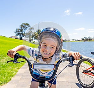 Portrait of cheerful cute kid with helmet riding his bike at the park