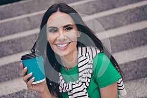 Portrait of cheerful cute woman dressed stylish clothes sitting on stairs drinking macchiato enjoying pastime spring