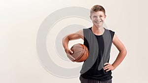 Portrait of cheerful disabled boy with Down syndrome smiling at camera while posing with basketball isolated over white