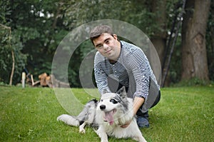 Portrait of cheerful down syndrome adult man playing with dog outdoors in backyard.