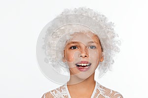 Portrait of a cheerful, energetic eight-year-old girl in a white wig and with white freckles