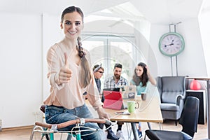 Portrait of a cheerful female entrepreneur showing thumbs up