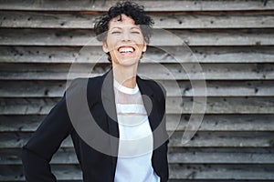 Portrait of cheerful female entrepreneur wearing suit while standing against wall