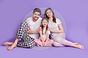 Portrait of cheerful full family daddy mommy offspring daughter generation wearing pajama sitting on floor upbringing