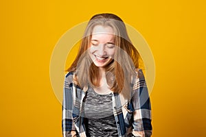 Portrait of a cheerful girl. Happy smiling teenage girl on a yellow background