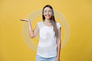 Portrait of a cheerful girl holding copyspace on the palm isolated on a yellow background