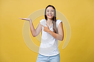 Portrait of a cheerful girl holding copyspace on the palm isolated on a yellow background