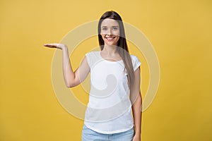 Portrait of a cheerful girl holding copyspace on the palm isolated on a yellow background