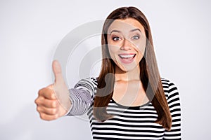 Portrait of cheerful girl showing her thumb up screaming wearing striped sweater  over white background