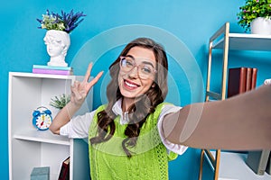 Portrait of cheerful girl toothy smile make selfie demonstrate v-sign isolated on blue color background