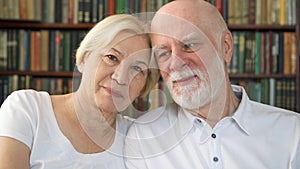 Portrait of cheerful good-looking senior couple sitting on sofa at home. Having good time relaxing.