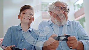 Portrait of cheerful grandson and grandfather playing video game in living room