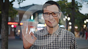 Portrait of cheerful guy showing OK hand gesture and smiling in urban street