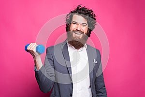 Portrait of cheerful handsome man wearing suit and working with small dumbbell, fitness concept