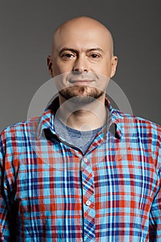 Portrait of cheerful handsome middle-aged man in plaid shirt looking at camera smiling over grey background.