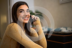 Portrait of cheerful happy pretty young woman talking on phone holding smartphone close to ear. Smiling adult girl using her