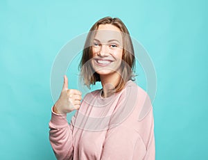 Portrait of a cheerful happy woman showing thumbs up