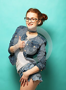 Portrait of a cheerful happy woman showing thumbs up over blue background