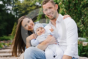 Portrait of a cheerful happy young family with a little son resting in the park in spring