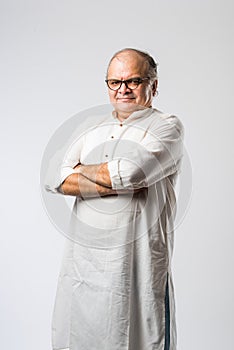 Portrait of cheerful Indian senior old man pointing or presenting or in hands folded pose