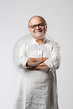 Portrait of cheerful Indian senior old man pointing or presenting or in hands folded pose