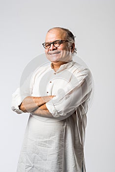 Portrait of cheerful Indian senior old man pointing or presenting or in hands folded pose