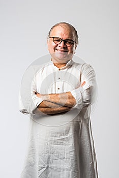 Portrait of cheerful Indian senior old man pointing or presenting or in hands folded pose