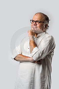 Portrait of cheerful Indian senior old man pointing or presenting or in hands folded pose