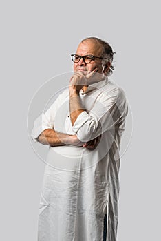 Portrait of cheerful Indian senior old man pointing or presenting or in hands folded pose