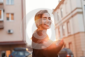 Portrait of a cheerful joyful beautiful young woman with a cute smile in fashionable black clothes outdoors in the city