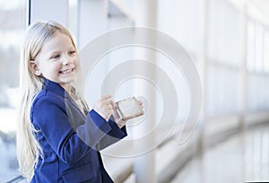 Portrait of cheerful little girl in blue jacket with smartphone