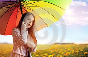 Portrait of a cheerful little girl relaxing under an umbrella