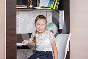 Portrait of a cheerful little girl studying in the first class. Workplace of young pupil. Happy child getting ready to do homework
