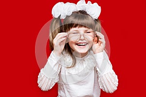 Portrait of cheerful little girl in very big glasses and white bow. Concept of eyesight or teaching