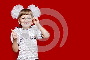 Portrait of cheerful little girl in very big glasses and white bows show thumb up