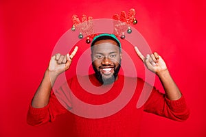 Portrait of cheerful man with deer elk antlers pointing at them bought on winter sales discounts wearing stylish trendy