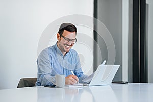 Portrét veselý muž s volanie na prenosný počítač počítač veselý podnikateľ prenosný počítač v jasný kancelária priestor mladý 
