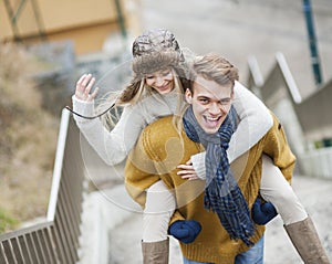 Portrait of cheerful man piggybacking woman on stairway