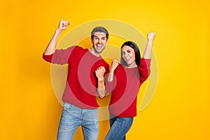 Portrait of cheerful man and woman raise his her fists scream yeah celebrate victory wear red pullover denim jeans