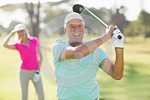 Portrait of cheerful mature golfer holding golf club