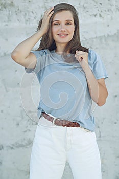 Portrait of cheerful mature woman standing against grey wall. Smiling carefree woman looking at camera.