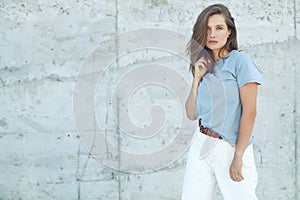 Portrait of cheerful mature woman standing against grey wall. Smiling carefree woman looking at camera.