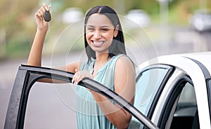 Portrait of a cheerful mixed race woman holding keys to her new car. Hispanic woman looking happy buying her first car