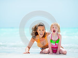 Portrait of cheerful mother and baby girl on beach