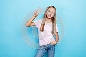 Portrait of cheerful nice girl toothy smile hand fingers demonstrate v-sign  on blue color background