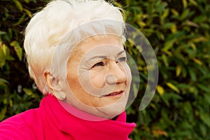 Portrait of a cheerful old lady over green background.