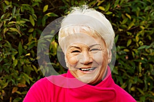 Portrait of a cheerful old lady over green background.