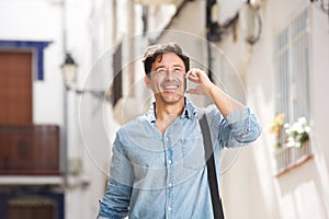 Cheerful older man walking outdoors and making a phone call