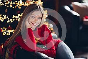 Portrait of cheerful positive young happy girl teenager touch cheek enjoying sitting armchair photo session during xmas