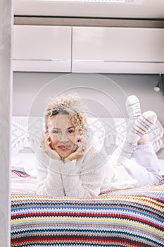 Portrait of cheerful pretty adult woman laying and smiling inside her camper van in the bedroom. Concept of travel and living off